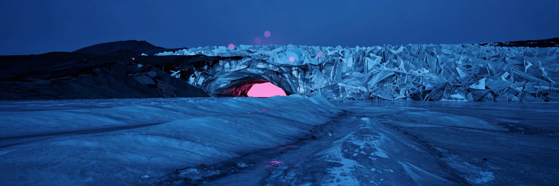 Ultra-wide at a distant vantage looking back at the cave entrance at dusk, the cave mouth visible as a bright pinkish opening in a vast ice landscape.