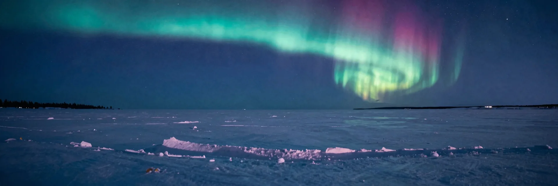 Ultra-wide vast snowy landscape stretching to the horizon under a wide aurora arc