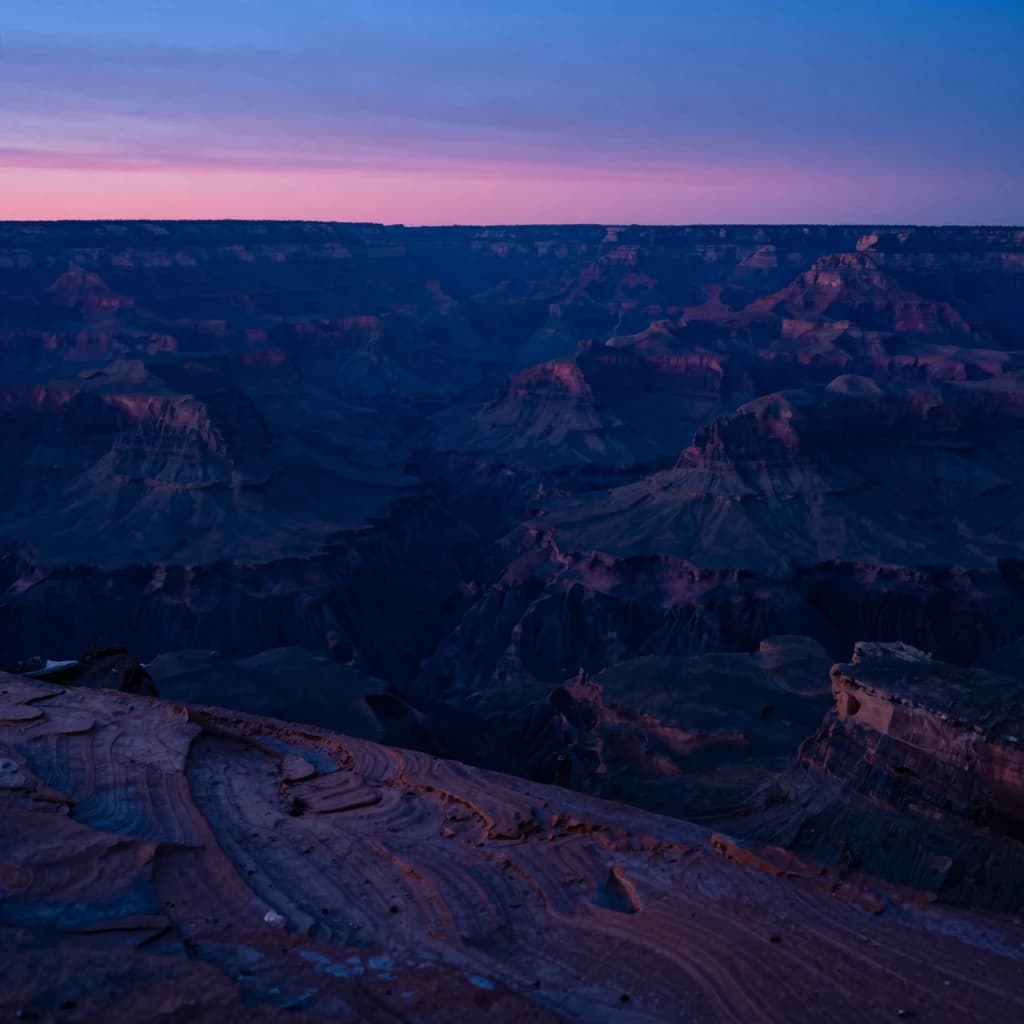 A deep canyon in shadow with a single thin horizontal strip of sky visible far above, canyon walls filling the lower frame in deep blue shadow, sunset glow on the highest ridge.