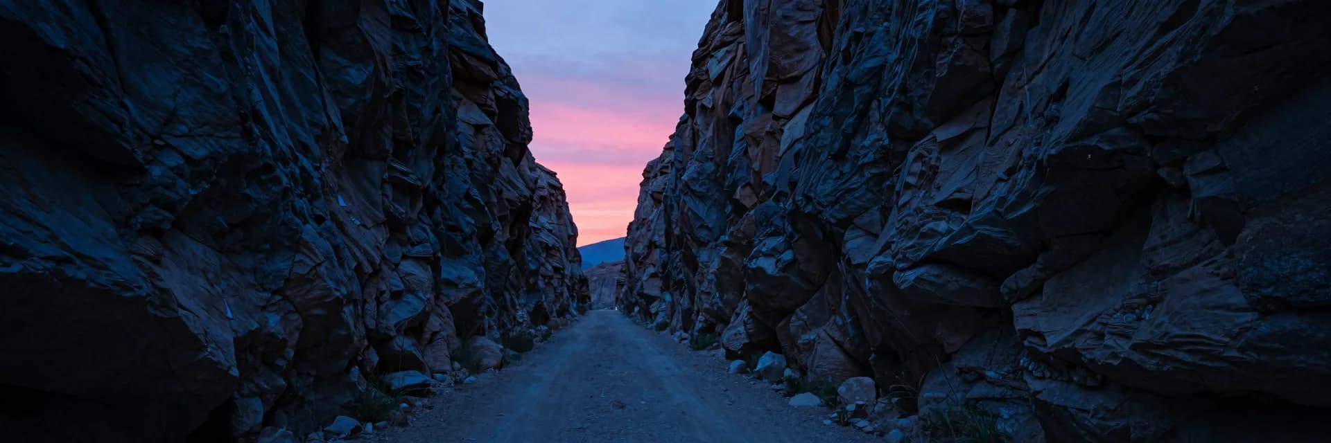 Ultra-wide canyon receding to a vanishing point between steep dusk walls