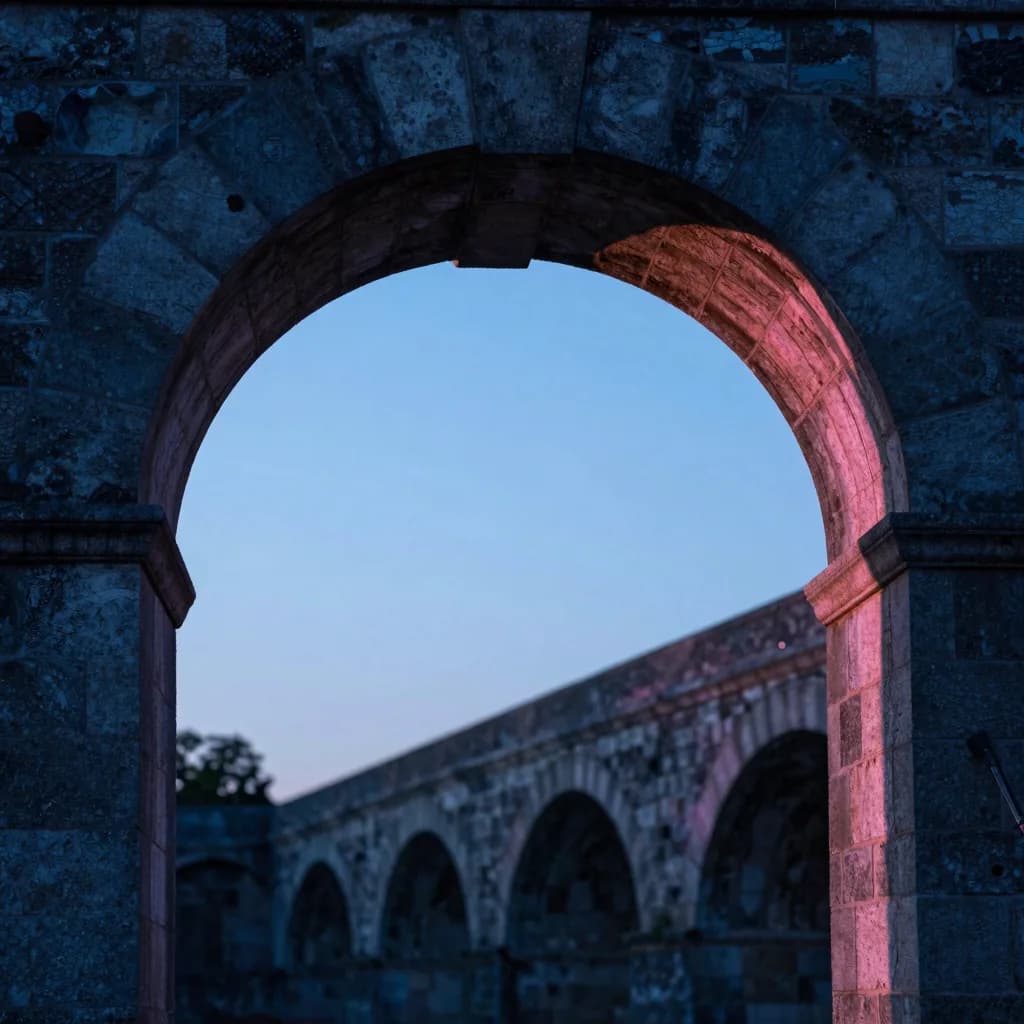From directly underneath one arch of the bridge looking up at the curve overhead, weathered stone keystones visible.
