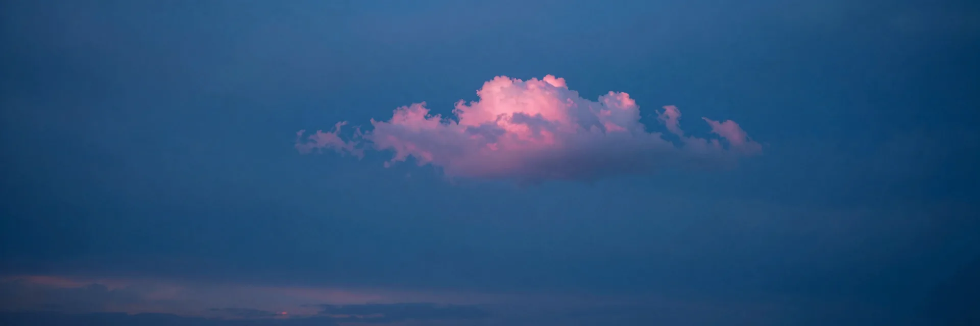Ultra-wide pure-atmosphere of the cloudy dusk sky with a single distinct pinkish cloud floating in the cool blue field, no landscape in frame, atmospheric break shot.