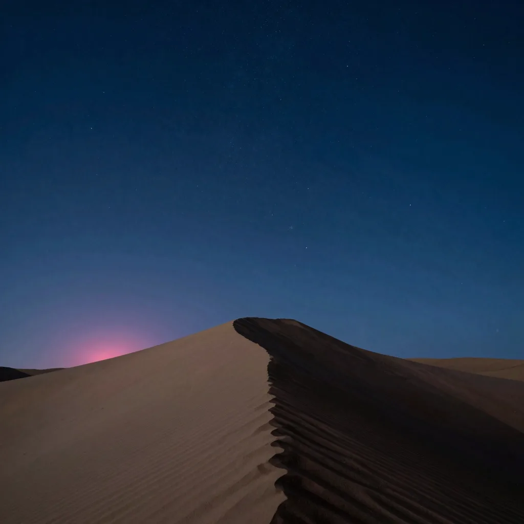 A single tall sand dune rises against a dark starry sky in vertical emphasis.
