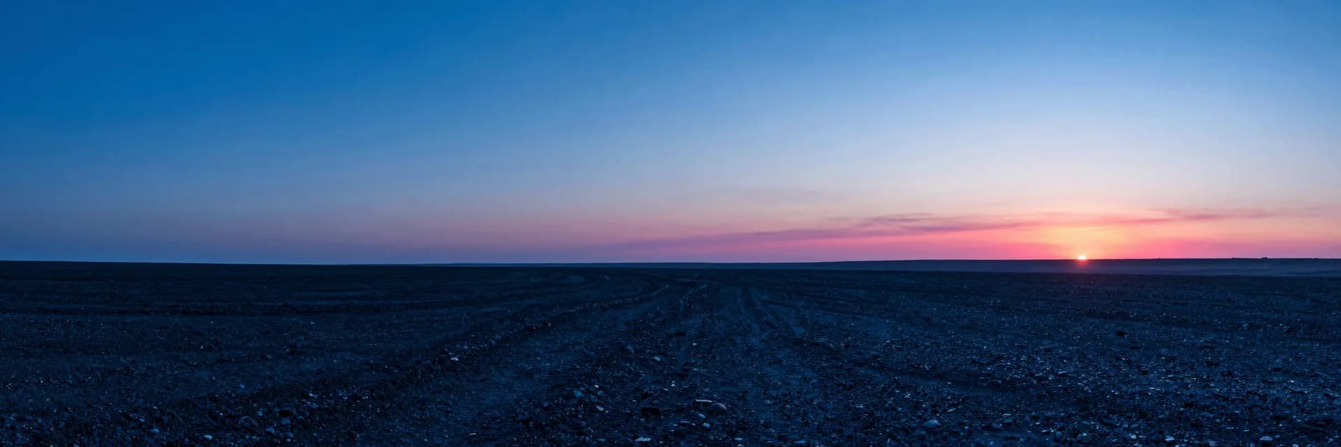 Wide atmospheric haze over a dim plain, single distant translucent monolith barely visible through electric-blue mist, hot-pink ember on the far horizon.
