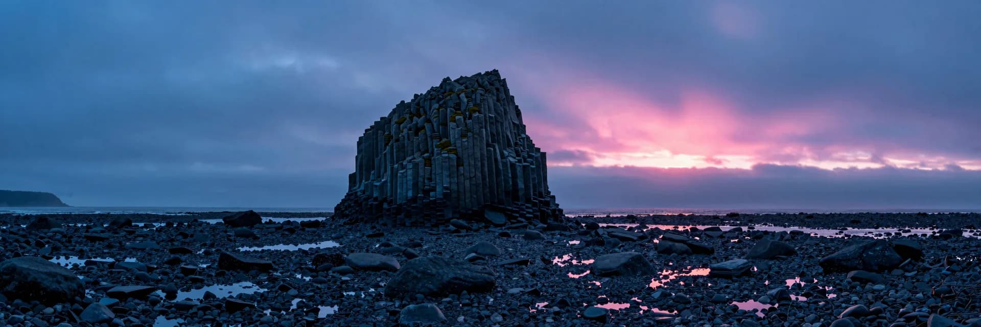 ultra-wide strip of coastal sea stack or arch under electric-blue sky with hot-pink sunset - companion image for the Klaviyo vs Omnisend decision for a small catalog