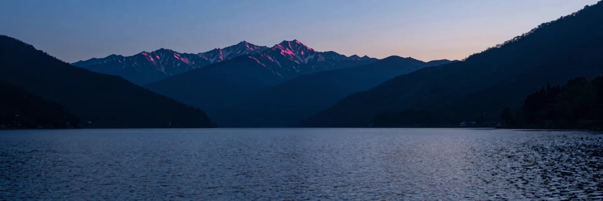 Ultra-wide distant mountain range stretching across the twilight horizon.