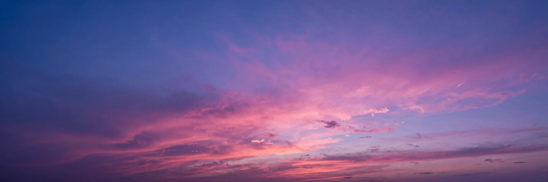 Pure ultra-wide cloud composition at sunset, vibrant pink and magenta clouds stretching across the entire frame, no horizon visible.
