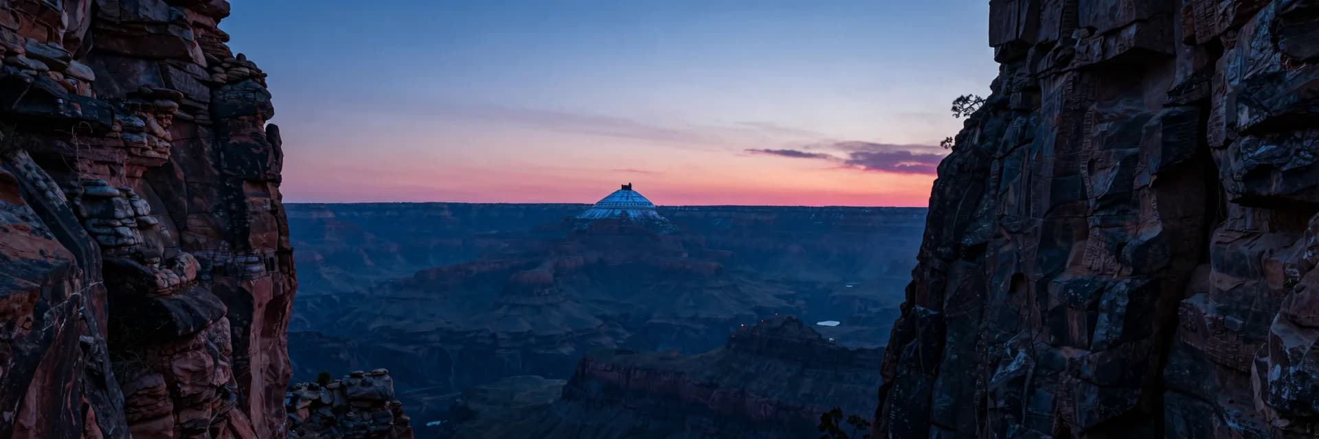 Ultra-wide view showing the canyon walls receding on both sides framing a distant snow-capped mountain with the small dark castle silhouette at the summit, full composition.