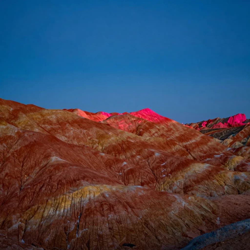 A single colorful eroded hill standing alone against an open empty sky.