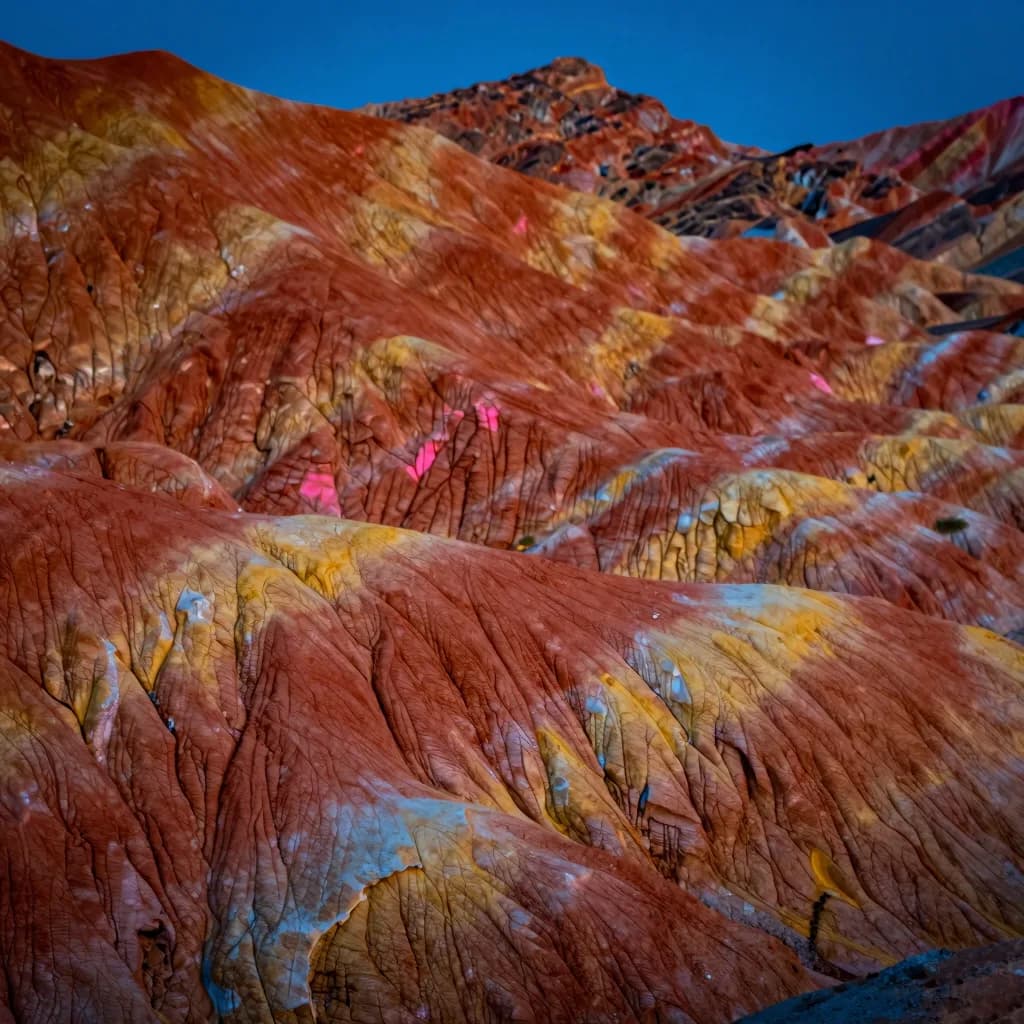Macro close-up of layered mineral striations showing intricate red, orange, and yellow geological texture.