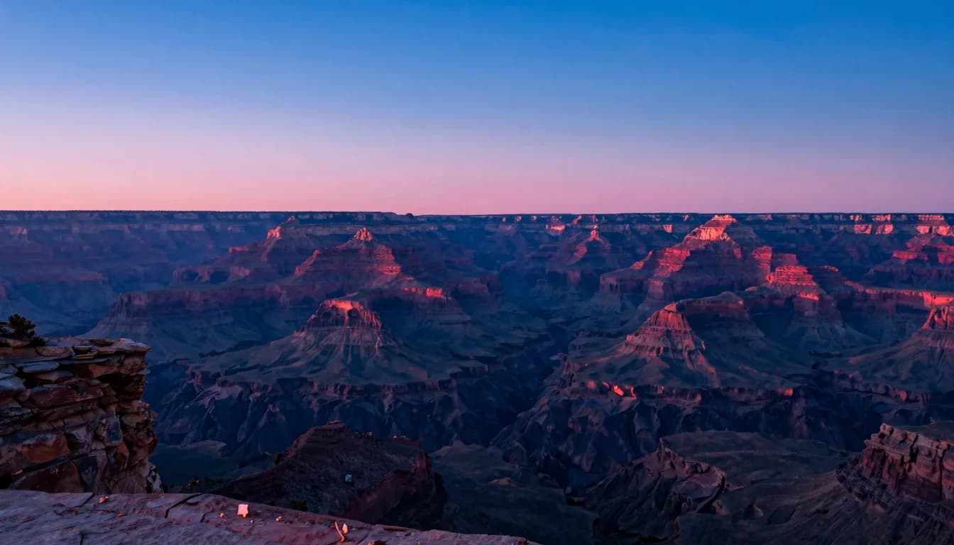 Most distant canyon walls visible across the chasm at sunset, layered ridges receding into atmospheric haze.