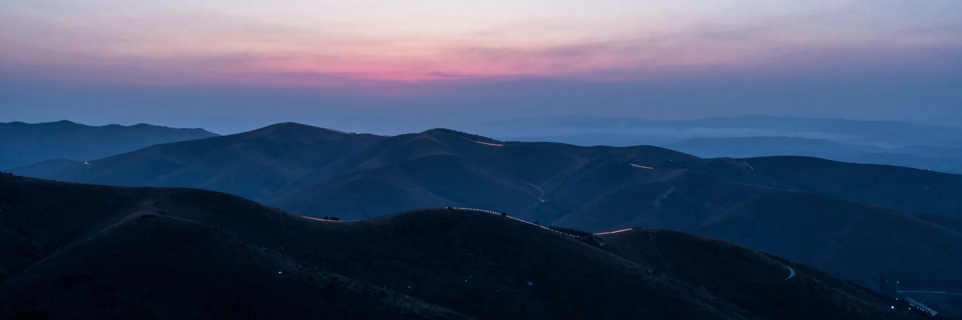 Ultra-wide pure-atmosphere of the misty layered hills at dusk, no terraces or lamps, hills receding into haze under the gradient sky.