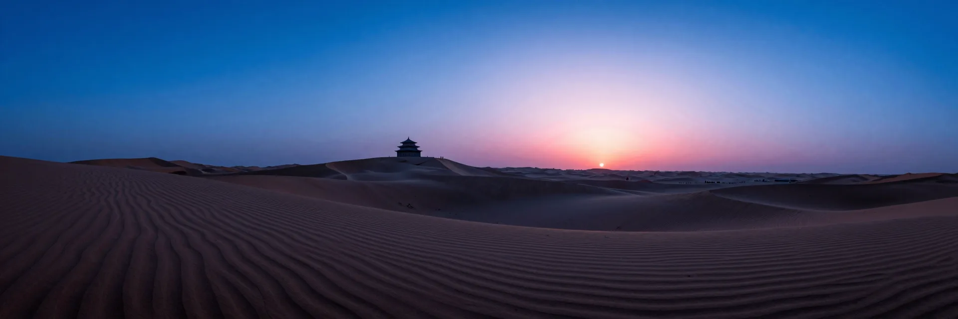 Ultra-wide of rippled sand dunes with leading lines stretching toward the distant temple silhouette small on the horizon.