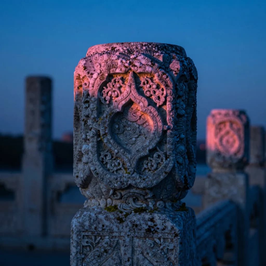 Close-up of the carved top of a single stone pillar at sunset showing intricate carved patterns with salt erosion and moss in the carving recesses.