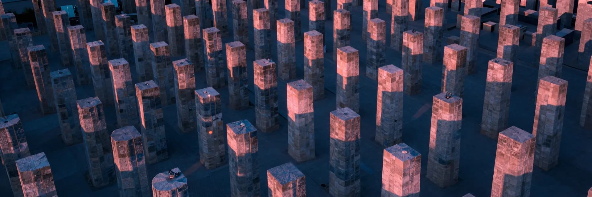 Ultra-wide aerial directly above a grid pattern of sandstone pillars at dusk, the regular geometry visible from this elevated vantage.