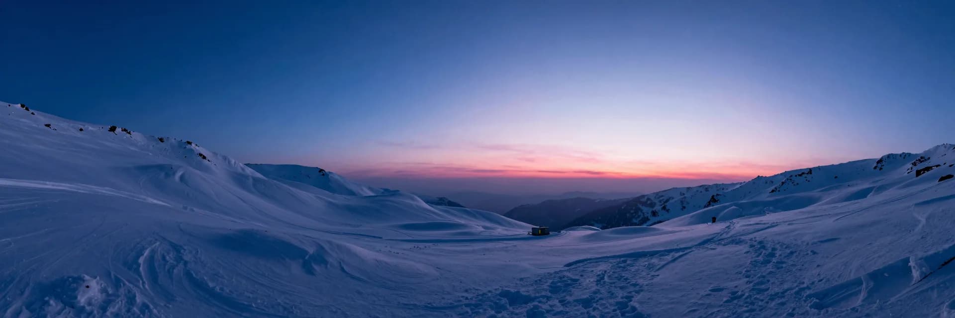 Atmospheric wide landscape at dusk, deep electric blue sky over a vast quiet plain with a low pink horizon glow.