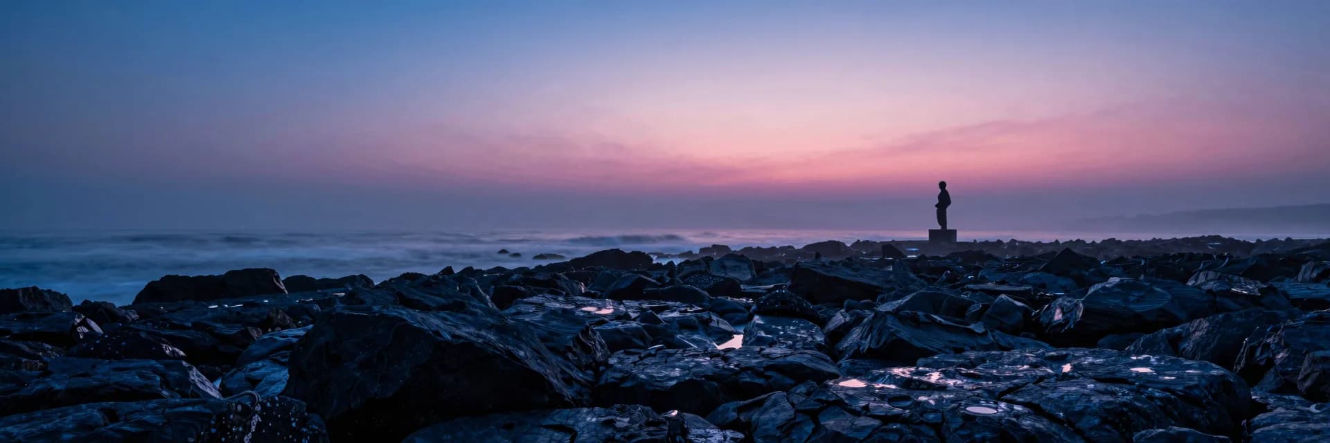 Ultra-wide rocky shoreline receding to vanishing point at dusk