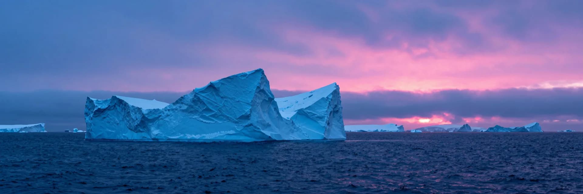 ultra-wide strip of electric-blue ice cliff strata with hot-pink sunset accent - hero image for the stopped billing hourly essay