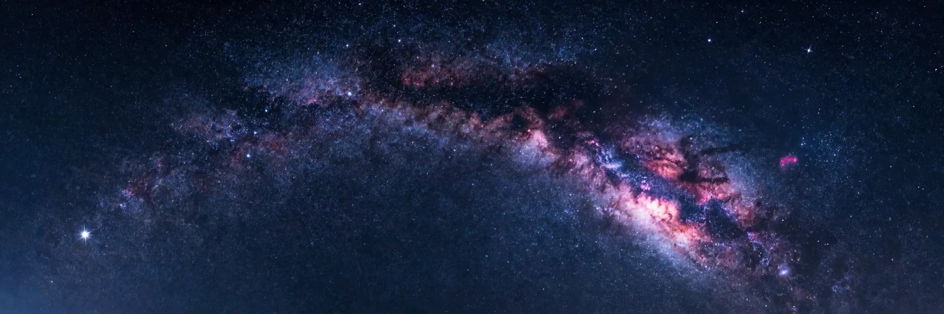 Ultra-wide vast cosmic sky with dunes appearing as a small element along the lower edge of the frame.