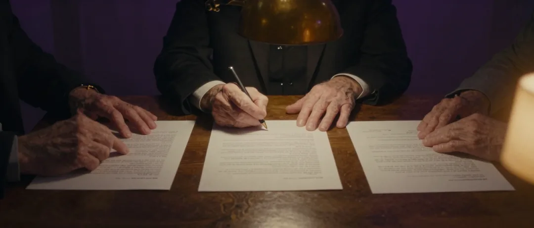 Close framing of hands signing a will across a conference table.