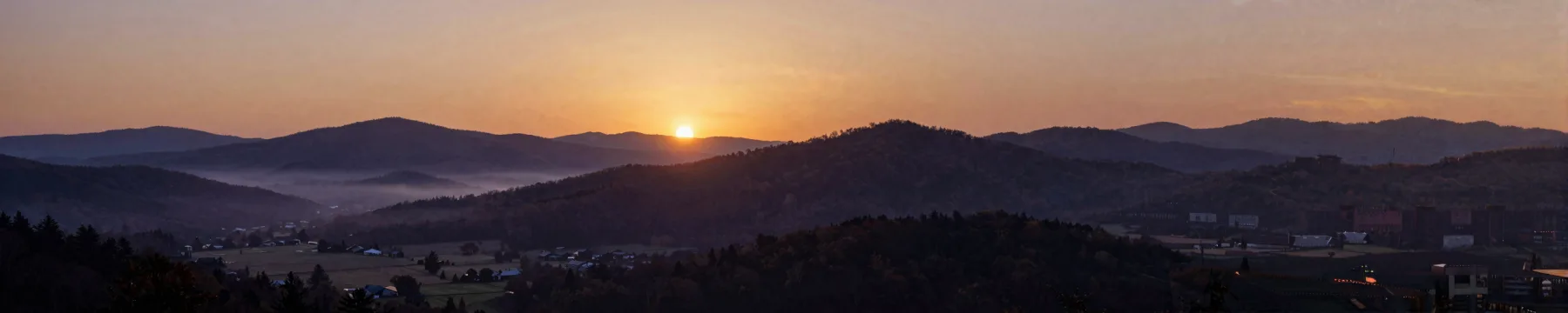 Farms scattered across a mountain valley at dawn.